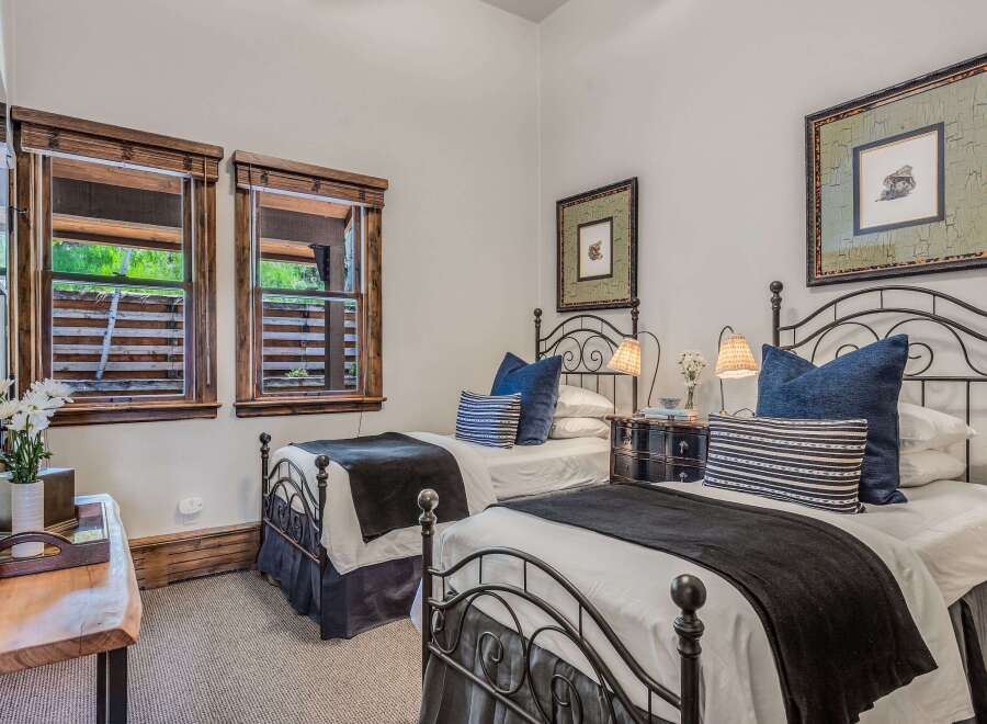 This charming bedroom features two twin beds with elegant black metal frames, perfect for accommodating guests.
