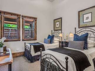 This charming bedroom features two twin beds with elegant black metal frames, perfect for accommodating guests.