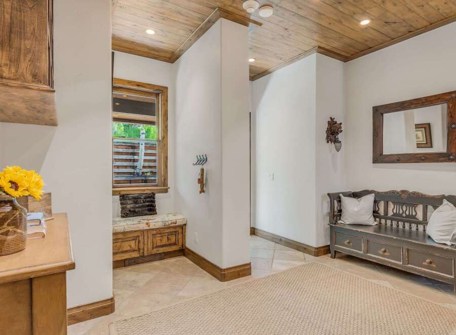 Step into this charming entryway featuring a rustic wooden ceiling and a cozy built-in bench with storage.