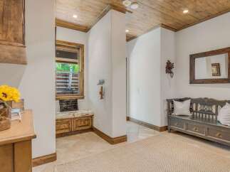 Step into this charming entryway featuring a rustic wooden ceiling and a cozy built-in bench with storage.