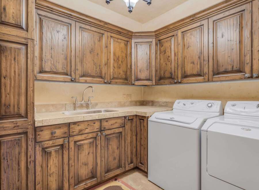 This laundry room boasts custom knotty alder cabinetry with a rich, dark stain, offering ample storage and a luxurious feel.