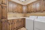 This laundry room boasts custom knotty alder cabinetry with a rich, dark stain, offering ample storage and a luxurious feel.