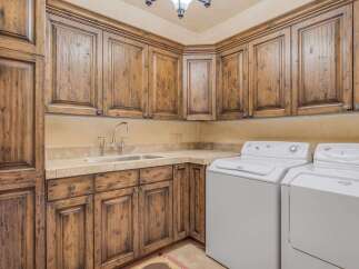 This laundry room boasts custom knotty alder cabinetry with a rich, dark stain, offering ample storage and a luxurious feel.