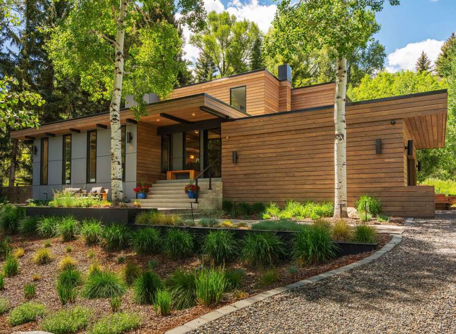 Experience modern luxury in this stunning home featuring a sleek wood-paneled exterior and expansive windows that invite the natural surroundings indoors.