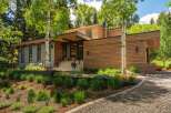 Experience modern luxury in this stunning home featuring a sleek wood-paneled exterior and expansive windows that invite the natural surroundings indoors.