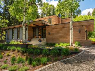 Experience modern luxury in this stunning home featuring a sleek wood-paneled exterior and expansive windows that invite the natural surroundings indoors.