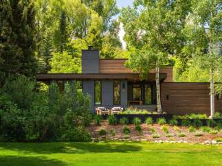Experience modern luxury in this stunning home, featuring a sleek gray facade complemented by warm wood accents.
