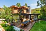Experience luxurious outdoor living with this modern home featuring a spacious deck, built-in grill, and comfortable seating areas perfect for entertaining.