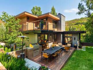 Experience luxurious outdoor living with this modern home featuring a spacious deck, built-in grill, and comfortable seating areas perfect for entertaining.