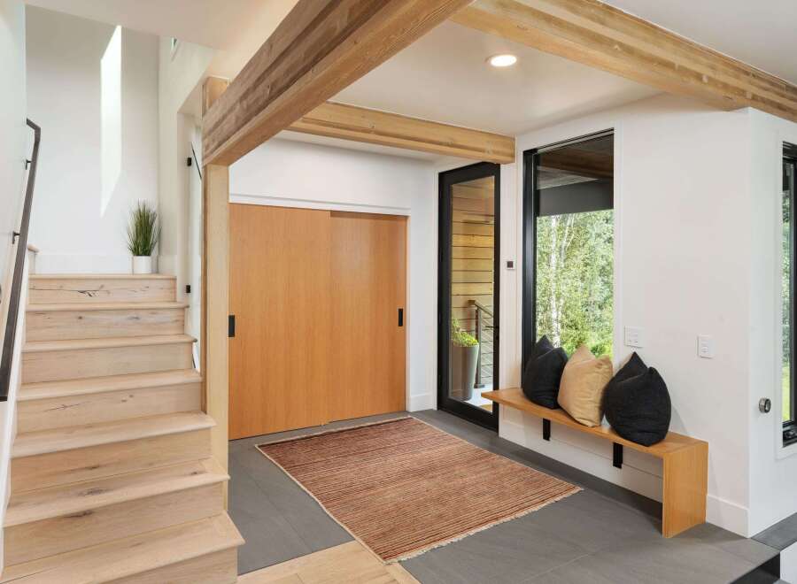 Step into this modern entryway featuring a sleek wooden staircase and a large sliding door for ample natural light.