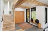 Step into this modern entryway featuring a sleek wooden staircase and a large sliding door for ample natural light.
