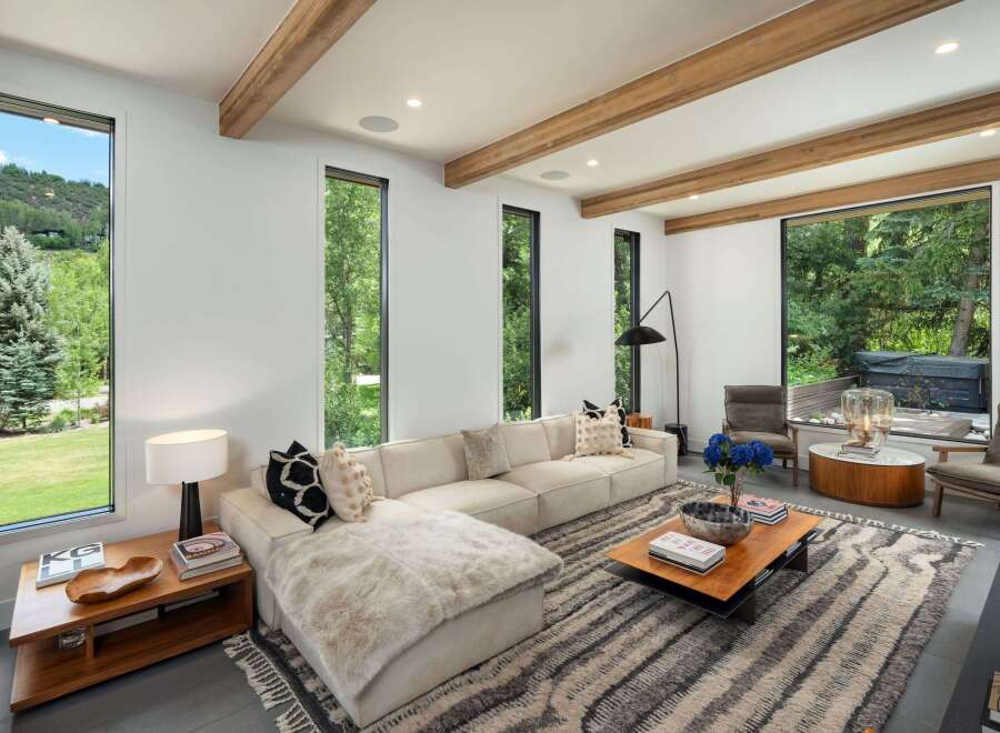Experience modern luxury in this stunning living room, featuring expansive windows that frame breathtaking mountain and forest views.