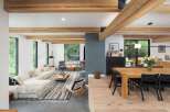 Experience modern living in this open-concept space featuring exposed wooden beams and large windows that flood the area with natural light.