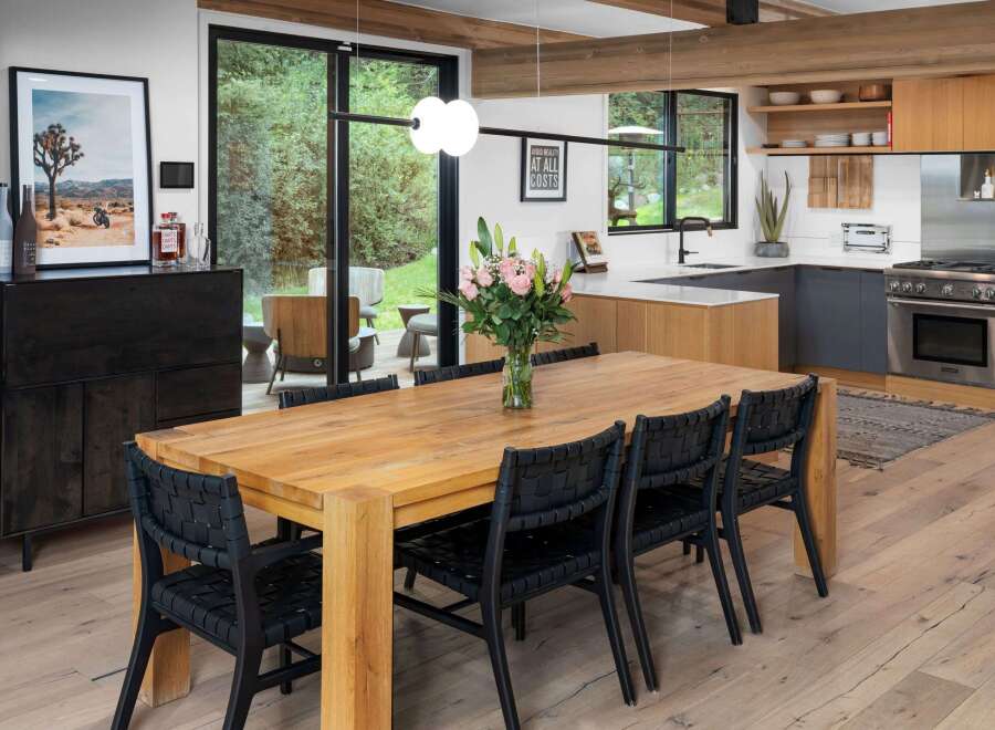 This modern dining room features a large, rustic wooden table with black woven chairs, perfect for family gatherings.