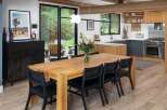 This modern dining room features a large, rustic wooden table with black woven chairs, perfect for family gatherings.