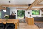 Experience modern living in this stunning open-concept dining and kitchen area, featuring exposed wooden beams and a sleek, minimalist design.