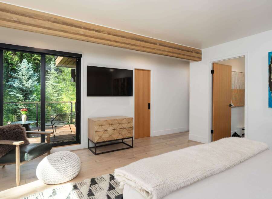 Experience luxurious mountain living with this stunning bedroom featuring a large flat-screen TV and a stylish geometric dresser.
