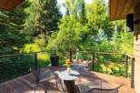 Enjoy serene outdoor living on this spacious wooden deck, surrounded by lush greenery and mature trees.