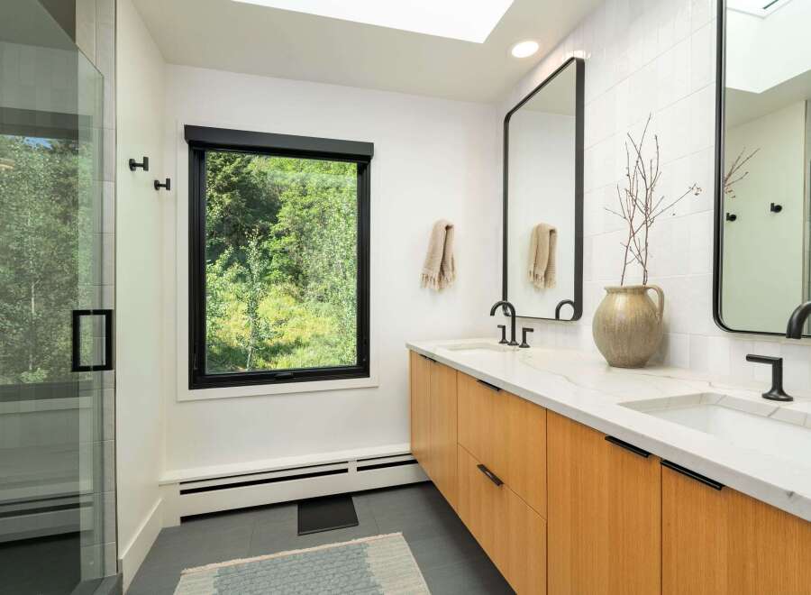 Experience modern luxury in this stunning bathroom featuring a spacious glass-enclosed shower and a sleek double vanity with natural wood cabinetry.