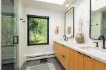 Experience modern luxury in this stunning bathroom featuring a spacious glass-enclosed shower and a sleek double vanity with natural wood cabinetry.