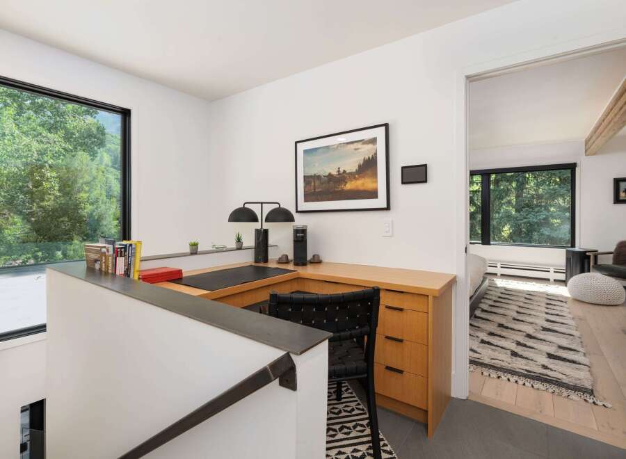 Discover a modern workspace with a large window offering serene forest views.