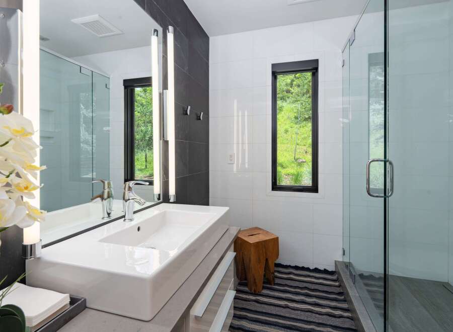 Experience modern luxury in this stunning bathroom featuring a sleek vessel sink atop a minimalist vanity.