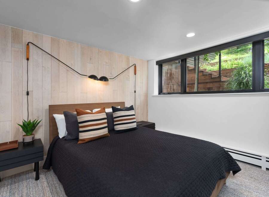 Experience modern comfort in this stylish bedroom, featuring a queen-sized bed with a dark quilted comforter and decorative striped pillows.