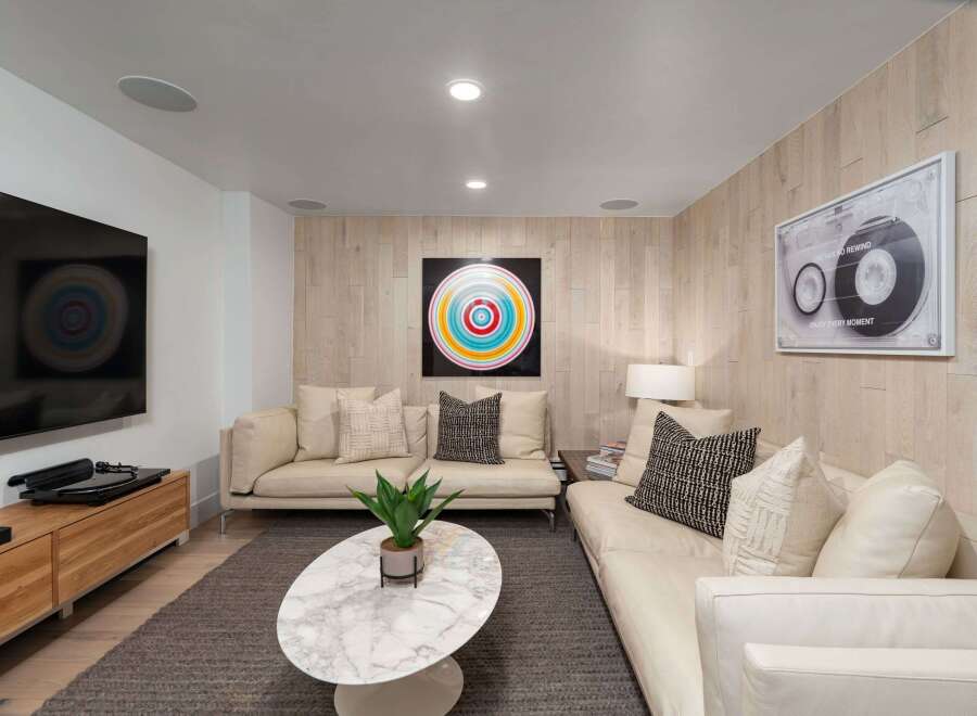 Experience modern living in this stylish living room, featuring a sleek entertainment center with a turntable and a large flat-screen TV.