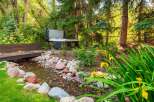 Escape to your private oasis with this stunning backyard featuring a luxurious hot tub nestled amongst lush greenery.
