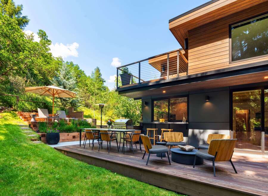 Experience seamless indoor-outdoor living with this stunning modern home featuring a spacious wooden deck perfect for entertaining.