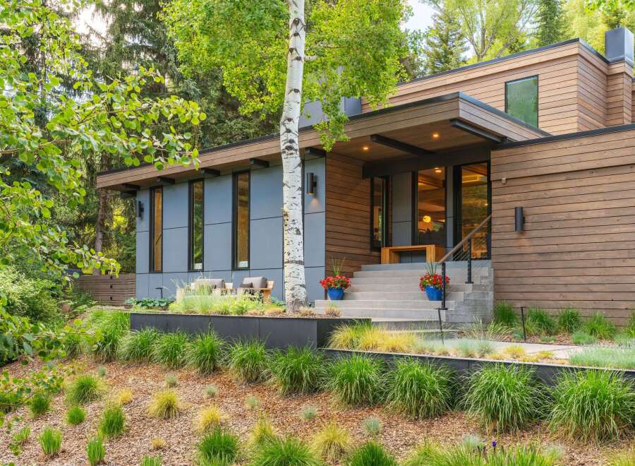 Experience modern luxury in this stunning home, featuring a striking facade of wood and gray paneling.