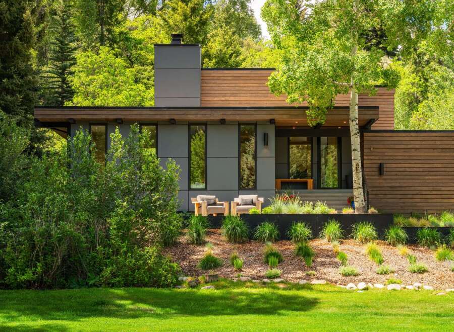 Experience modern luxury in this stunning home, featuring a sleek gray facade complemented by warm wood accents.