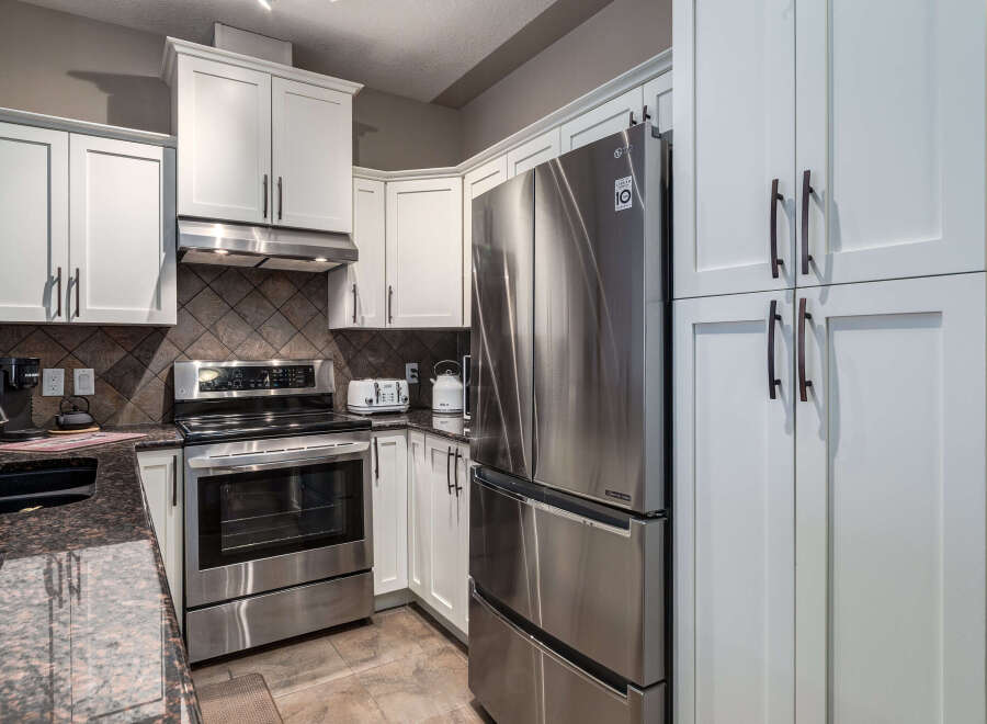 Discover this modern kitchen featuring sleek stainless steel appliances, including a French door refrigerator and a smooth-top range.