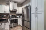 Discover this modern kitchen featuring sleek stainless steel appliances, including a French door refrigerator and a smooth-top range.