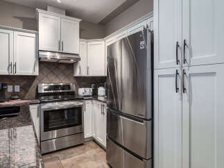 Discover this modern kitchen featuring sleek stainless steel appliances, including a French door refrigerator and a smooth-top range.