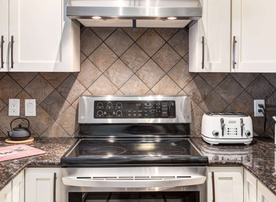 Experience modern convenience in this kitchen, featuring a sleek LG electric range with a digital display and a stylish white toaster.