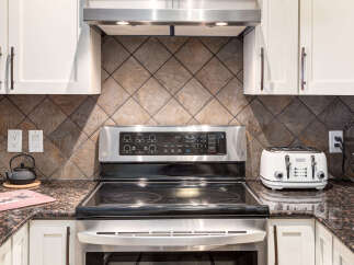 Experience modern convenience in this kitchen, featuring a sleek LG electric range with a digital display and a stylish white toaster.