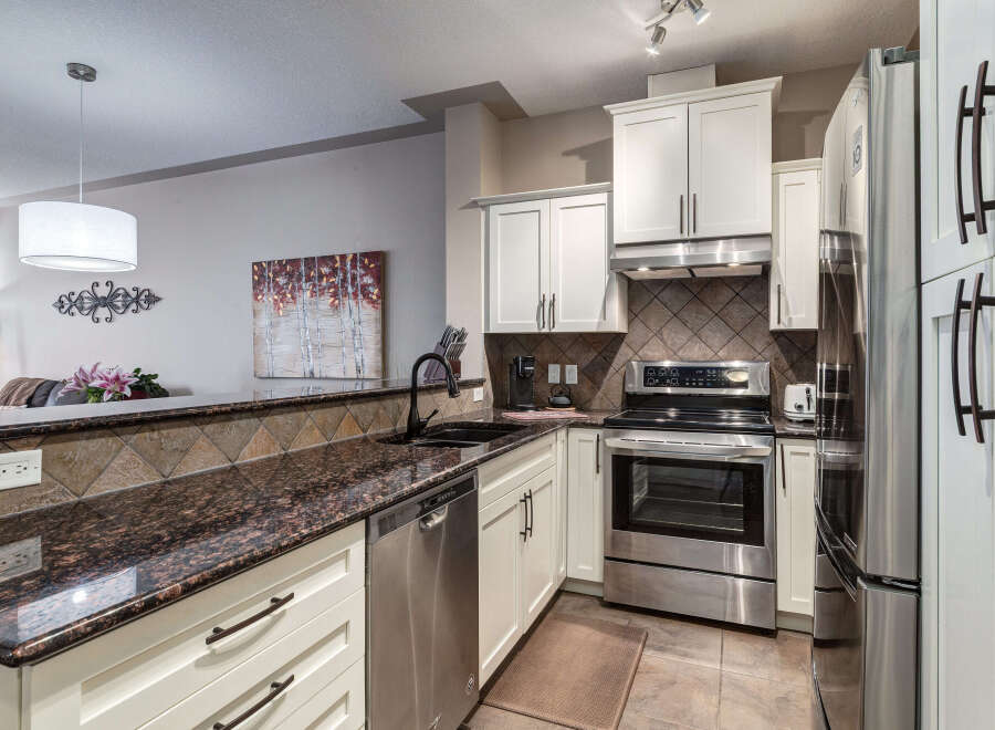 Discover this stunning kitchen featuring sleek white cabinetry complemented by a beautiful granite countertop and a stylish tile backsplash.
