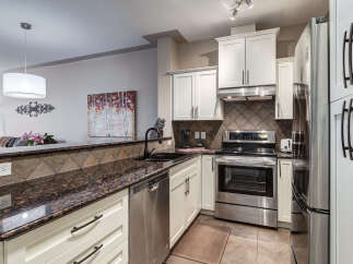 Discover this stunning kitchen featuring sleek white cabinetry complemented by a beautiful granite countertop and a stylish tile backsplash.