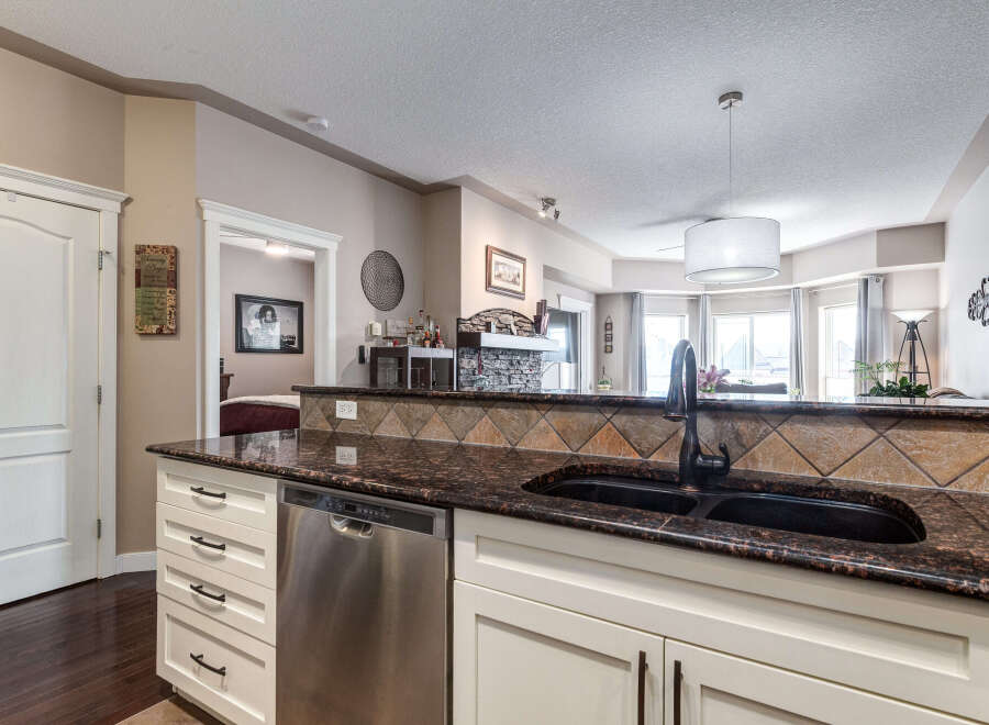 This stunning kitchen features a beautiful granite countertop with a double sink and a dark bronze faucet.