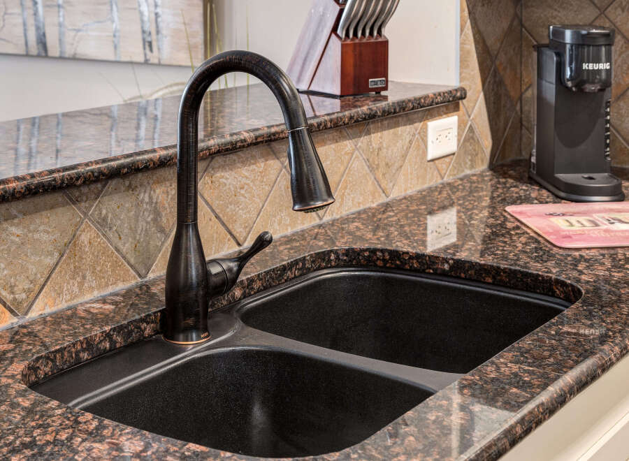Experience the elegance of this kitchen featuring a stunning granite countertop and a deep, double-basin sink.