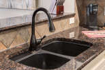 Experience the elegance of this kitchen featuring a stunning granite countertop and a deep, double-basin sink.