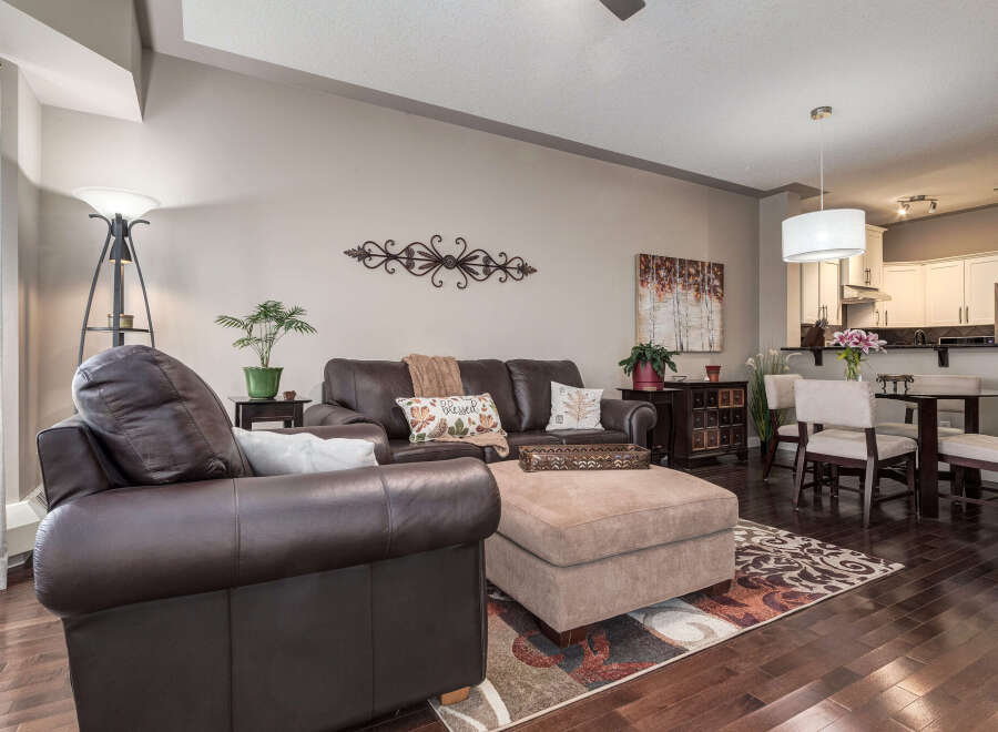 Experience comfortable living in this inviting open-concept space, featuring a spacious living area with plush leather seating and a stylish ottoman.