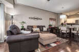 Experience comfortable living in this inviting open-concept space, featuring a spacious living area with plush leather seating and a stylish ottoman.