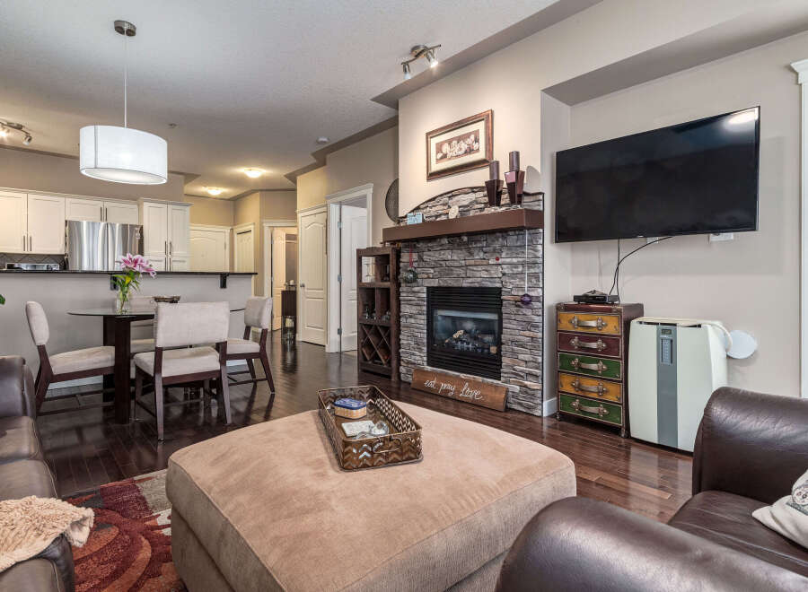 Experience comfort and style in this inviting living space, featuring a cozy stone fireplace and a large ottoman perfect for relaxation.