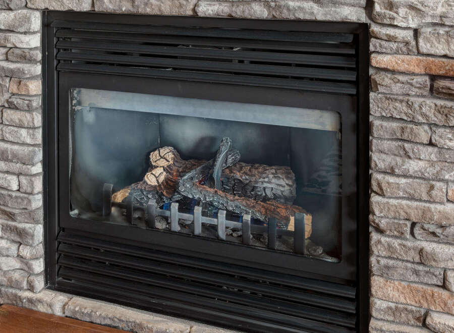 Cozy up by this beautiful gas fireplace, featuring realistic faux logs and a charming stone surround.