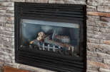 Cozy up by this beautiful gas fireplace, featuring realistic faux logs and a charming stone surround.