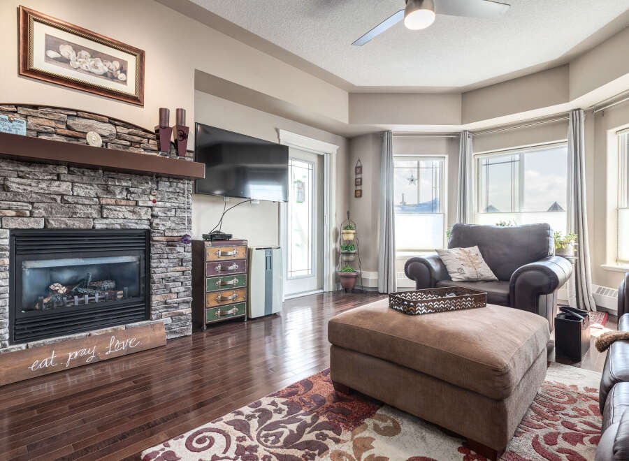 Cozy living room featuring a stone fireplace with a wooden mantel and a large flat-screen TV.