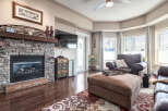 Cozy living room featuring a stone fireplace with a wooden mantel and a large flat-screen TV.