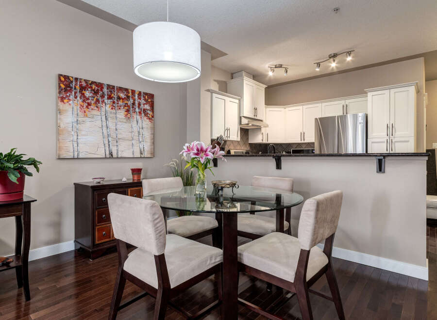 This dining area features a sleek glass-top dining table with four upholstered chairs, perfect for intimate meals.